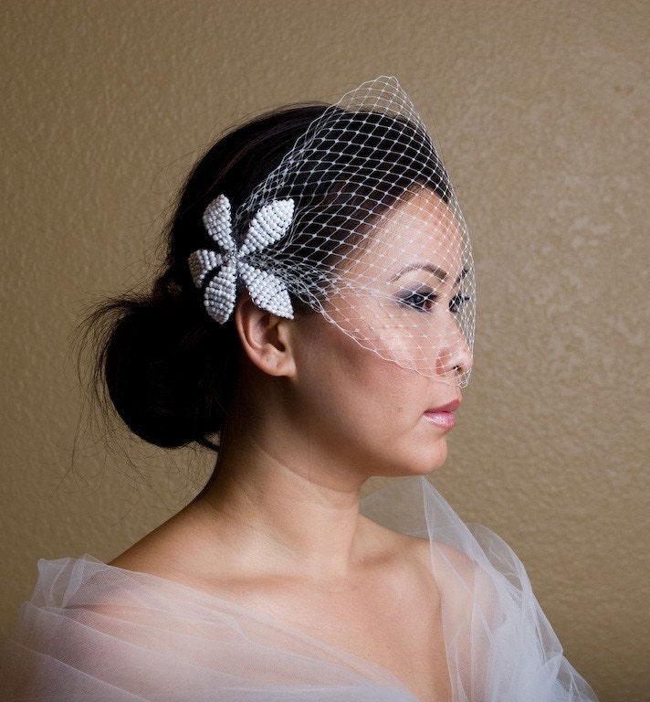 A fullyfeminine French tulle birdcage veil and handsculpted bead flower