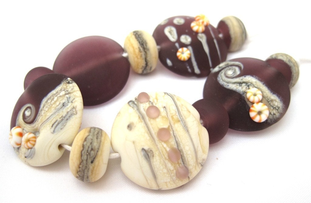 A set of eleven handmade lampwork beads. The set includes five 25mm etched lentils all slightly different and including silvered ivory decoration.