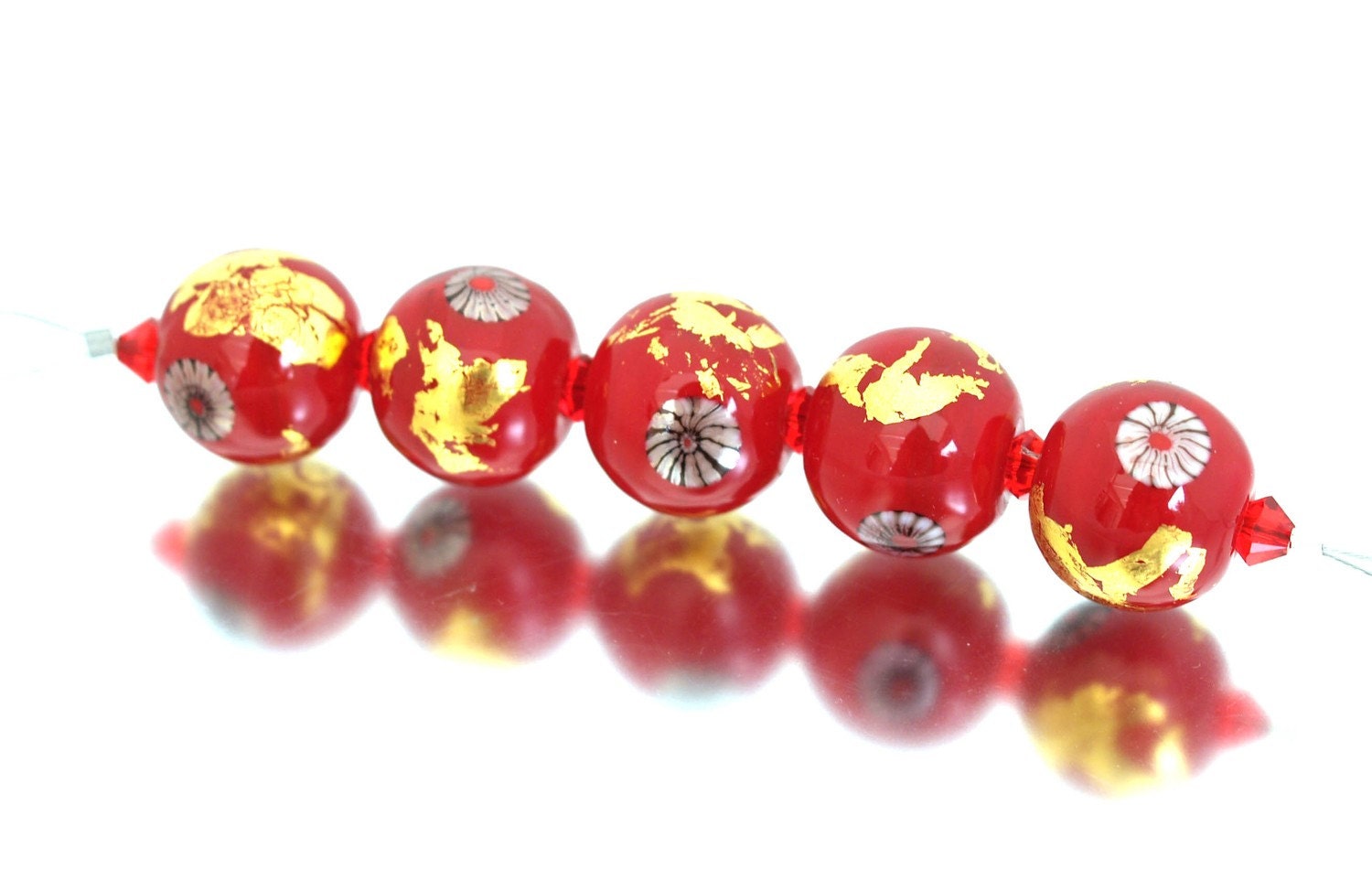 A set of five handmade glass beads in a beautiful scarlet red decorated with gold foil and murrini in black, white and red. This opulent set has an oriental look and would make a stunning piece of jewellery.