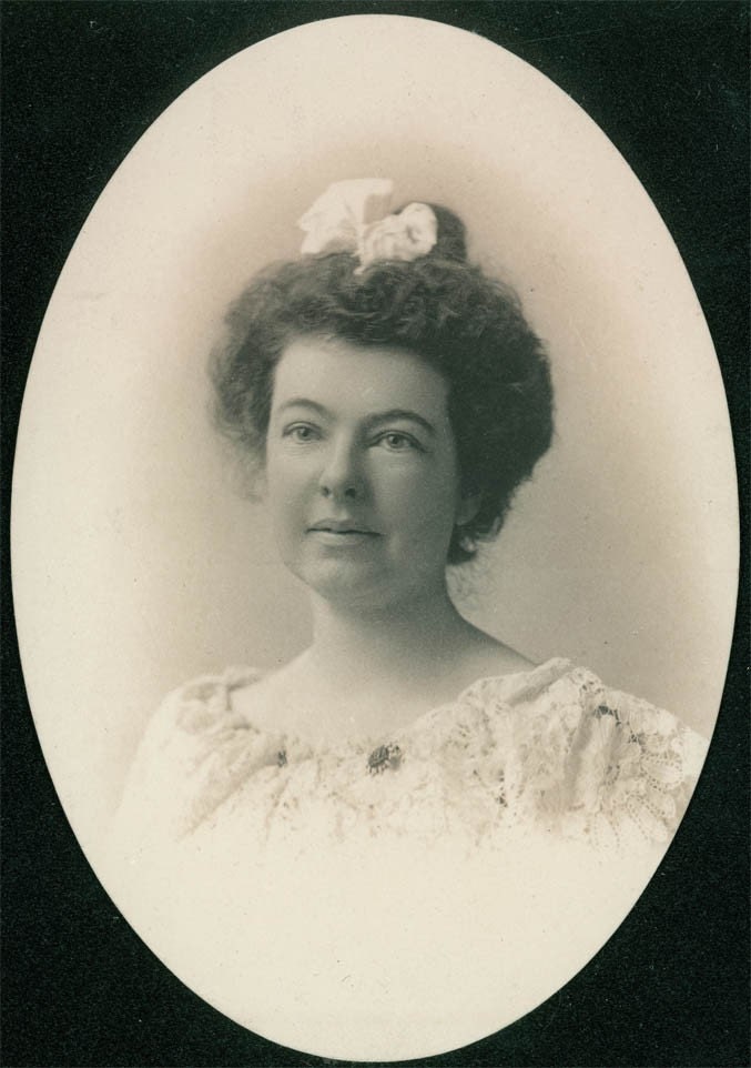 This is an original vintage oval photo of a woman with curly hair with a bow 